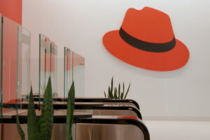 Red Hat anunció el lanzamiento de Red Hat AI Enterprise, una plataforma de inteligencia artificial orientada a la implementación y gestión de modelos, agentes y aplicaciones de IA en entornos de nube híbrida. La solución se integra en la cartera de Red Hat AI, que incluye Red Hat AI Inference Server, Red Hat OpenShift AI y Red Hat Enterprise Linux AI. La compañía también presentó Red Hat AI 3.3, una actualización que incorpora mejoras en distintas herramientas de su portafolio de inteligencia artificial. Según la empresa, estas soluciones buscan ofrecer una pila tecnológica que conecta la infraestructura basada en Linux y Kubernetes con capacidades de agentes para la gestión de sistemas de IA. De acuerdo con la compañía, el desarrollo de la inteligencia artificial empresarial ha evolucionado desde interfaces de chat hacia flujos de trabajo con agentes autónomos que requieren mayor integración en la infraestructura tecnológica. En este contexto, la empresa indicó que muchas organizaciones continúan en etapas piloto debido a herramientas fragmentadas e infraestructura inconsistente. Red Hat AI Enterprise busca abordar este escenario mediante la unificación del ciclo de vida de modelos y aplicaciones, lo que permite a los equipos de TI gestionar la inteligencia artificial como un sistema empresarial estandarizado. Plataforma para implementar IA en producción La plataforma incluye capacidades como inferencia de IA, ajuste y personalización de modelos, así como implementación y gestión de agentes. La solución puede operar con distintos modelos, hardware y entornos tecnológicos. Impulsada por Red Hat OpenShift, plataforma de aplicaciones en nube híbrida basada en Kubernetes, la herramienta está diseñada para ofrecer escalabilidad y consistencia operativa en diferentes entornos. En el caso de infraestructuras basadas en tecnología de NVIDIA, la compañía indicó que desarrolló junto a esta empresa Red Hat AI Factory con NVIDIA, que combina Red Hat AI Enterprise y NVIDIA AI Enterprise con el objetivo de facilitar la implementación de inteligencia artificial en producción. Entre las funciones destacadas de Red Hat AI Enterprise se encuentran el uso del motor de inferencia vLLM y el framework llm-d para implementaciones de modelos generativos en entornos de hardware híbrido. También incluye herramientas de observabilidad y gestión del ciclo de vida para apoyar procesos de gobernanza y mitigación de riesgos asociados al uso de IA. La plataforma también está diseñada para permitir el despliegue y administración de modelos, agentes y aplicaciones en entornos de nube híbrida. Actualizaciones en la plataforma Red Hat AI 3.3 La actualización Red Hat AI 3.3 introduce nuevas funciones dentro del portafolio de inteligencia artificial de la compañía. Entre las novedades se incluye la incorporación de modelos como Mistral-Large-3, Nemotron-Nano y Apertus-8B-Instruct, disponibles en el catálogo de OpenShift AI. La versión también permite implementar modelos como Ministral 3 y DeepSeek-V3.2, además de incorporar mejoras multimodales y optimizaciones en herramientas de desarrollo. Otra de las funciones anunciadas es una vista previa tecnológica de Modelos como Servicio (MaaS), que permitirá a los equipos de TI ofrecer acceso de autoservicio a modelos alojados de forma privada a través de un gateway de API. La actualización también amplía el soporte de hardware, incluyendo una vista previa tecnológica para inferencia de IA generativa en CPU Intel, certificación extendida para la arquitectura NVIDIA Blackwell Ultra y soporte para aceleradores AMD MI325X. Adicionalmente, Red Hat presentó Red Hat AI Python Index, un repositorio que reúne versiones reforzadas de herramientas utilizadas en el desarrollo de sistemas de inteligencia artificial, con el objetivo de facilitar la transición desde entornos de experimentación hacia procesos de producción. La plataforma también incorpora funciones de observabilidad y seguridad para monitorear el rendimiento y comportamiento de los modelos, incluyendo telemetría en tiempo real y una vista previa tecnológica de NeMo Guardrails integrada. Entre las funciones adicionales se incluye el acceso bajo demanda a recursos de GPU mediante orquestación inteligente, lo que permite a las organizaciones gestionar recursos de hardware agrupados y mantener el estado de trabajos de entrenamiento de larga duración.
