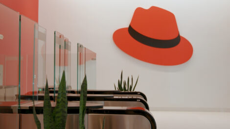 Red Hat anunció el lanzamiento de Red Hat AI Enterprise, una plataforma de inteligencia artificial orientada a la implementación y gestión de modelos, agentes y aplicaciones de IA en entornos de nube híbrida. La solución se integra en la cartera de Red Hat AI, que incluye Red Hat AI Inference Server, Red Hat OpenShift AI y Red Hat Enterprise Linux AI. La compañía también presentó Red Hat AI 3.3, una actualización que incorpora mejoras en distintas herramientas de su portafolio de inteligencia artificial. Según la empresa, estas soluciones buscan ofrecer una pila tecnológica que conecta la infraestructura basada en Linux y Kubernetes con capacidades de agentes para la gestión de sistemas de IA. De acuerdo con la compañía, el desarrollo de la inteligencia artificial empresarial ha evolucionado desde interfaces de chat hacia flujos de trabajo con agentes autónomos que requieren mayor integración en la infraestructura tecnológica. En este contexto, la empresa indicó que muchas organizaciones continúan en etapas piloto debido a herramientas fragmentadas e infraestructura inconsistente. Red Hat AI Enterprise busca abordar este escenario mediante la unificación del ciclo de vida de modelos y aplicaciones, lo que permite a los equipos de TI gestionar la inteligencia artificial como un sistema empresarial estandarizado. Plataforma para implementar IA en producción La plataforma incluye capacidades como inferencia de IA, ajuste y personalización de modelos, así como implementación y gestión de agentes. La solución puede operar con distintos modelos, hardware y entornos tecnológicos. Impulsada por Red Hat OpenShift, plataforma de aplicaciones en nube híbrida basada en Kubernetes, la herramienta está diseñada para ofrecer escalabilidad y consistencia operativa en diferentes entornos. En el caso de infraestructuras basadas en tecnología de NVIDIA, la compañía indicó que desarrolló junto a esta empresa Red Hat AI Factory con NVIDIA, que combina Red Hat AI Enterprise y NVIDIA AI Enterprise con el objetivo de facilitar la implementación de inteligencia artificial en producción. Entre las funciones destacadas de Red Hat AI Enterprise se encuentran el uso del motor de inferencia vLLM y el framework llm-d para implementaciones de modelos generativos en entornos de hardware híbrido. También incluye herramientas de observabilidad y gestión del ciclo de vida para apoyar procesos de gobernanza y mitigación de riesgos asociados al uso de IA. La plataforma también está diseñada para permitir el despliegue y administración de modelos, agentes y aplicaciones en entornos de nube híbrida. Actualizaciones en la plataforma Red Hat AI 3.3 La actualización Red Hat AI 3.3 introduce nuevas funciones dentro del portafolio de inteligencia artificial de la compañía. Entre las novedades se incluye la incorporación de modelos como Mistral-Large-3, Nemotron-Nano y Apertus-8B-Instruct, disponibles en el catálogo de OpenShift AI. La versión también permite implementar modelos como Ministral 3 y DeepSeek-V3.2, además de incorporar mejoras multimodales y optimizaciones en herramientas de desarrollo. Otra de las funciones anunciadas es una vista previa tecnológica de Modelos como Servicio (MaaS), que permitirá a los equipos de TI ofrecer acceso de autoservicio a modelos alojados de forma privada a través de un gateway de API. La actualización también amplía el soporte de hardware, incluyendo una vista previa tecnológica para inferencia de IA generativa en CPU Intel, certificación extendida para la arquitectura NVIDIA Blackwell Ultra y soporte para aceleradores AMD MI325X. Adicionalmente, Red Hat presentó Red Hat AI Python Index, un repositorio que reúne versiones reforzadas de herramientas utilizadas en el desarrollo de sistemas de inteligencia artificial, con el objetivo de facilitar la transición desde entornos de experimentación hacia procesos de producción. La plataforma también incorpora funciones de observabilidad y seguridad para monitorear el rendimiento y comportamiento de los modelos, incluyendo telemetría en tiempo real y una vista previa tecnológica de NeMo Guardrails integrada. Entre las funciones adicionales se incluye el acceso bajo demanda a recursos de GPU mediante orquestación inteligente, lo que permite a las organizaciones gestionar recursos de hardware agrupados y mantener el estado de trabajos de entrenamiento de larga duración.